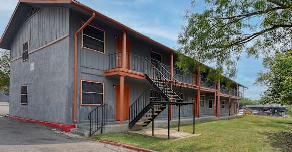 the exterior of an apartment building with stairs and a sidewalk at The Crossings at Montrose Apartments, San Antonio, Texas