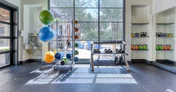 A gym with a row of exercise balls and weight plates.
