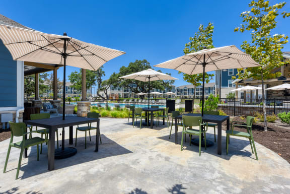 a patio with tables and umbrellas and chairs and a pool at Estraya Boerne, Boerne
