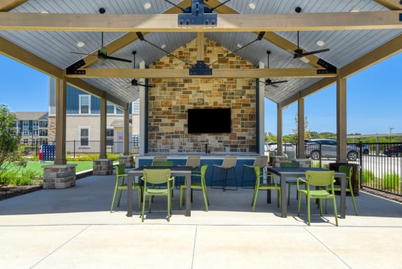 a patio with tables and chairs under a pavilion with a fireplace