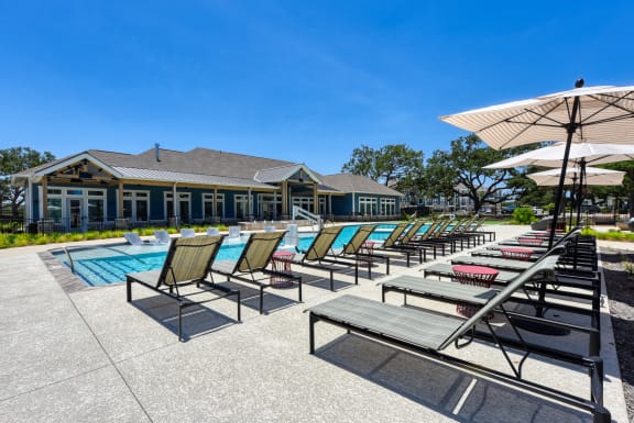a pool with chairs and umbrellas and a building in the background at Estraya Boerne, Boerne, TX, 78006