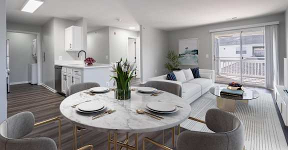 A modern dining room with a round marble table and grey chairs.