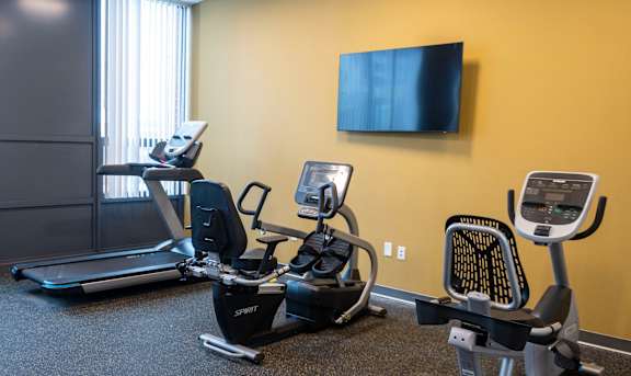 A gym with a treadmill, elliptical trainer and a stationary bike at Highpoint Towers Apartments, Erie, 16502