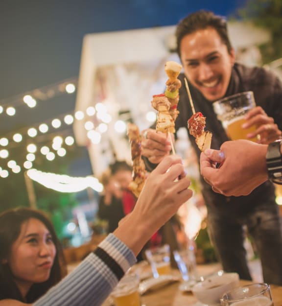 Group of Friends Toasting with Kabobs at Outdoor Party