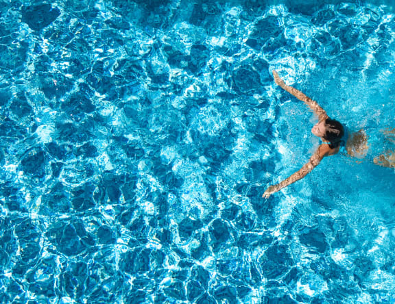 woman legs relaxing in water in a swimming pool at Casa Del Amo Apartments, California
