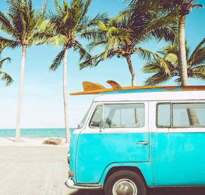 a blue van parked on the beach with a surfboard on top at Copa Ladeene Apartments, California