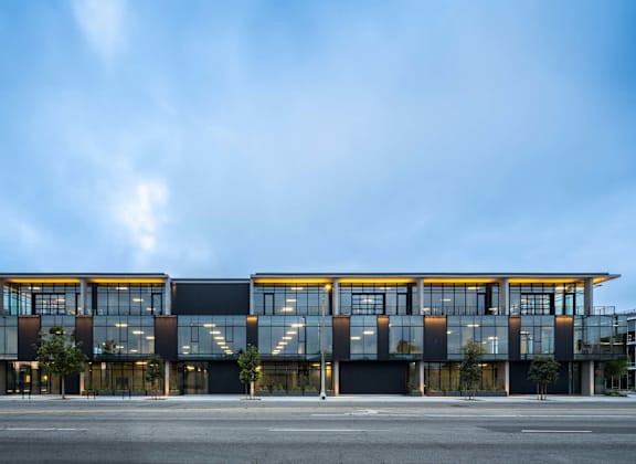 A modern building with a glass facade and a large mural on the side.