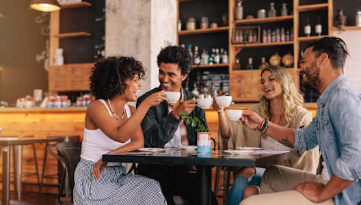 Four people are sitting around a table in a cafe.