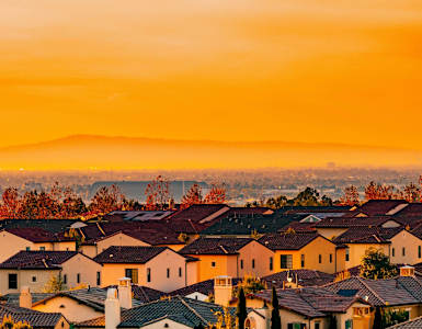 A sunset view of a neighborhood with houses and trees.