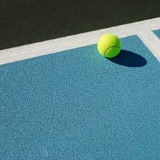 A tennis ball is on a blue court.