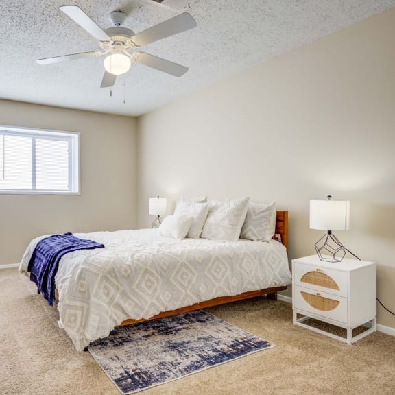 The Pearl at Highland Village Apartments and Townhomes for rent in Jackson, MS photo of a bedroom with a bed and a ceiling fan