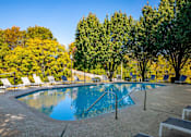 Thumbnail 24 of 28 - a swimming pool with chairs around it and trees in the background at Landmark at Lyncrest Reserve Apartments, Nashville, TN