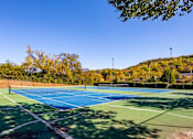 Thumbnail 25 of 28 - two tennis courts with trees in the background on a sunny day at Landmark at Lyncrest Reserve Apartments, Nashville, TN