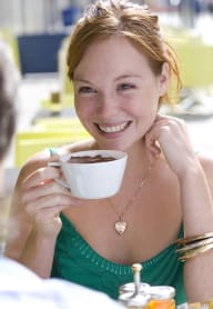 a woman sitting at a table with a cup of coffee