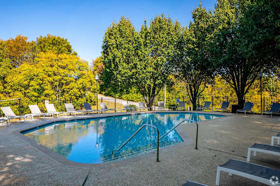 a swimming pool with chairs around it and trees in the background at Landmark at Lyncrest Reserve Apartments, Nashville, TN