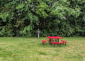 Thumbnail 26 of 28 - Picnic table and benches in a grassy area with trees in the background. at Landmark at Lyncrest Reserve Apartments, Nashville, TN