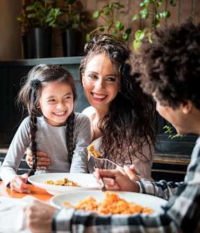 A family of three is having a meal together at a table.