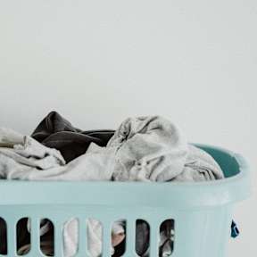 a blue laundry basket filled with folded clothes