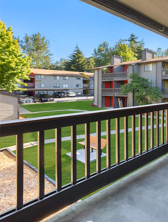 A balcony with a black railing overlooks a courtyard and other buildings.