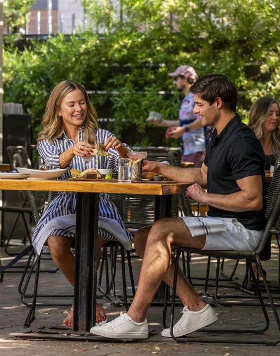a man and woman eating outside 