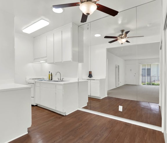 a kitchen with white cabinets and a ceiling fan at Olive Tree Apartments, Torrance California