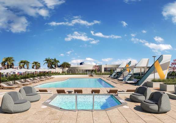 A large swimming pool surrounded by lounge chairs and palm trees.at Volar Apartments, Irvine California
