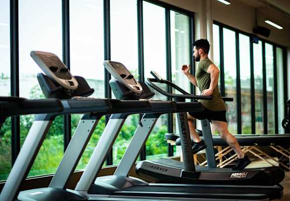 A man is running on a treadmill in a gym.