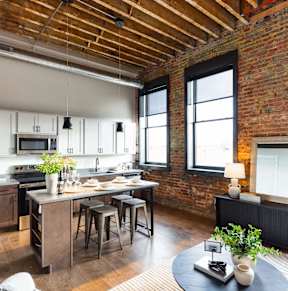 A kitchen with a brick wall and wooden ceiling.at Plant 1 Lofts, N. Newton