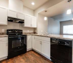 A kitchen with white cabinets and a bar area with stools. at Danamere Village, Iowa, 50047