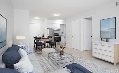 a living room with a couch and a table with a kitchen in the background