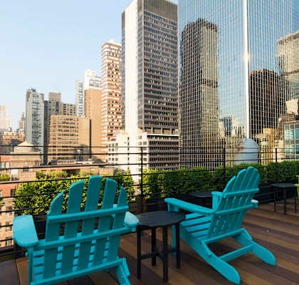 a deck with chairs and a table overlooking a city
