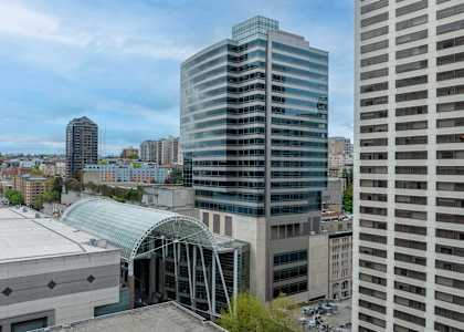 A cityscape with a large building in the foreground and a glass structure in the middle ground.