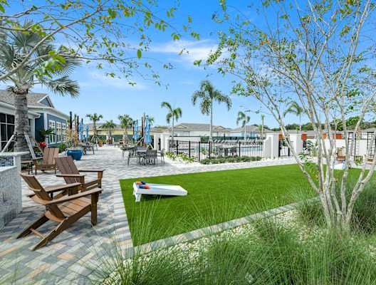 a courtyard with a lawn and tables and chairs