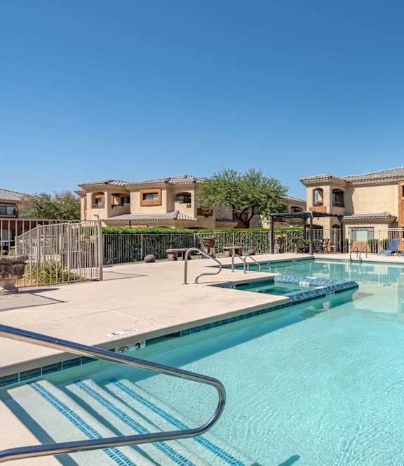 A swimming pool in front of a building with a clear blue sky at Sereno Townhomes, Glendale, Arizona.