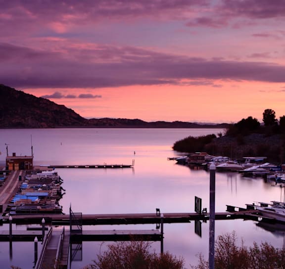 A serene dock with boats and a calm lake at sunset.