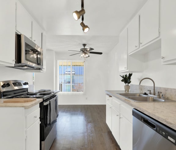 a kitchen with white cabinets and stainless steel appliances  at Casa De Oro Apartments, California