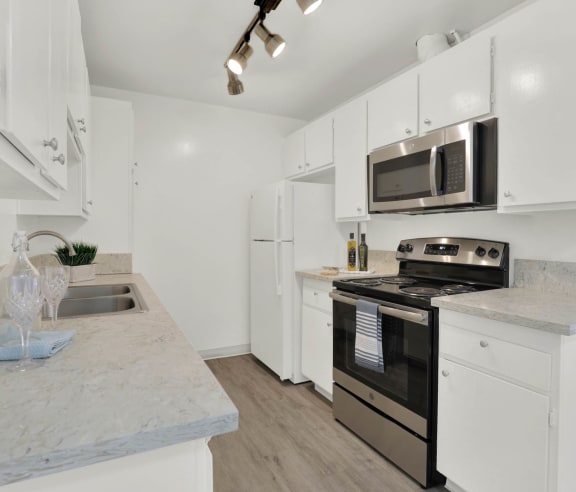 a kitchen with white cabinets and stainless steel appliances at Copa Ladeene Apartments, Torrance, CA 90505