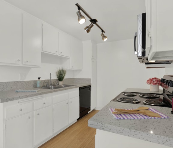 a kitchen with granite counter tops and white cabinets at Copa Triana Apartments, Torrance