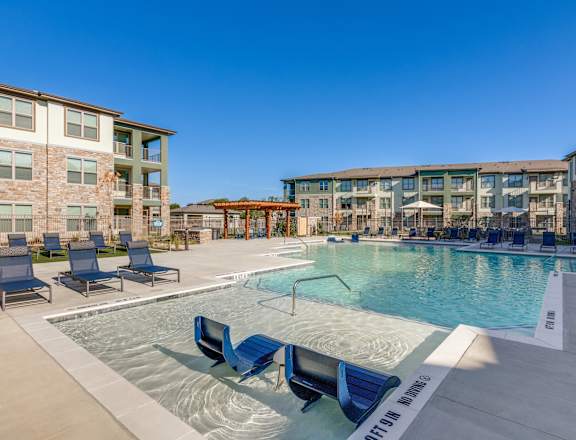A swimming pool with lounge chairs and a building in the background.