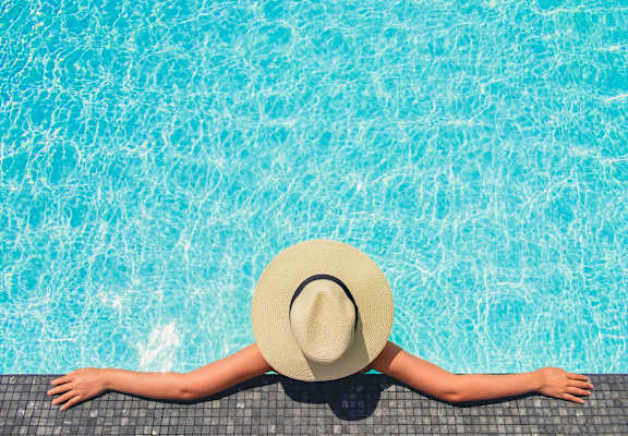 A person in a hat is relaxing by the pool. at Residences at the Landing, Texas