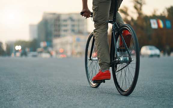 A blue bicycle with a brown seat is leaning against a textured wall.