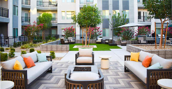 A patio with a couch, chairs, and a table in front of a building.
