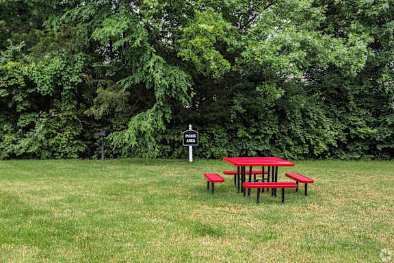 Picnic table and benches in a grassy area with trees in the background. at Landmark at Lyncrest Reserve Apartments, Nashville, TN