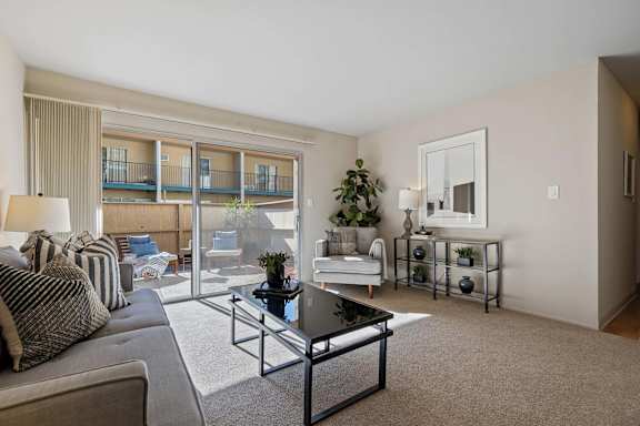 A living room with a couch, a coffee table, and a balcony.