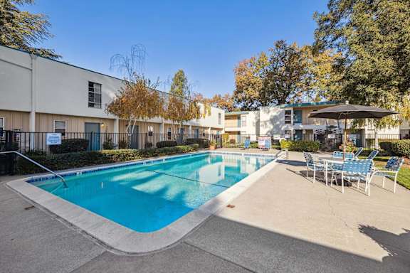 A large outdoor swimming pool surrounded by chairs and trees.