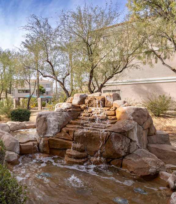 A small waterfall in a garden with rocks and shrubs.at Vintage at Scottsdale, SCOTTSDALE, AZ 85260