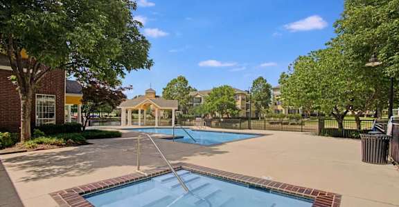 A swimming pool surrounded by a brick border with a diving board.