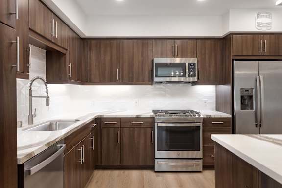 A modern kitchen with dark wood cabinets and stainless steel appliances. at Elements Apartments*, Irvine