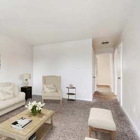 A living room with a couch, chair, and a table with candles on it.