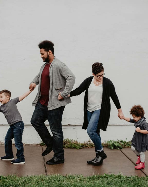 a family holding hands and walking down the sidewalk